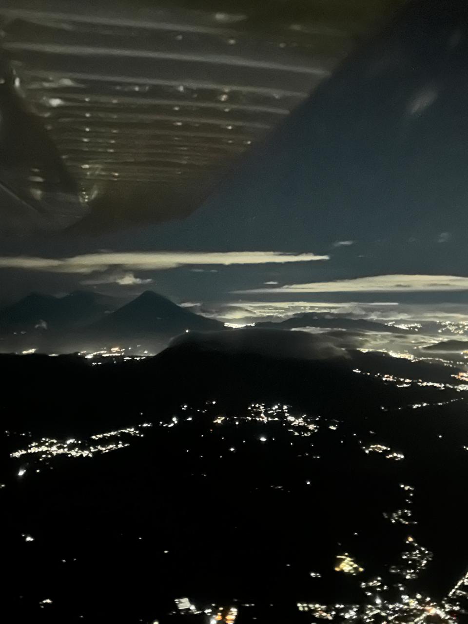 Volcanic silhouettes with city lights at night from cockpit
