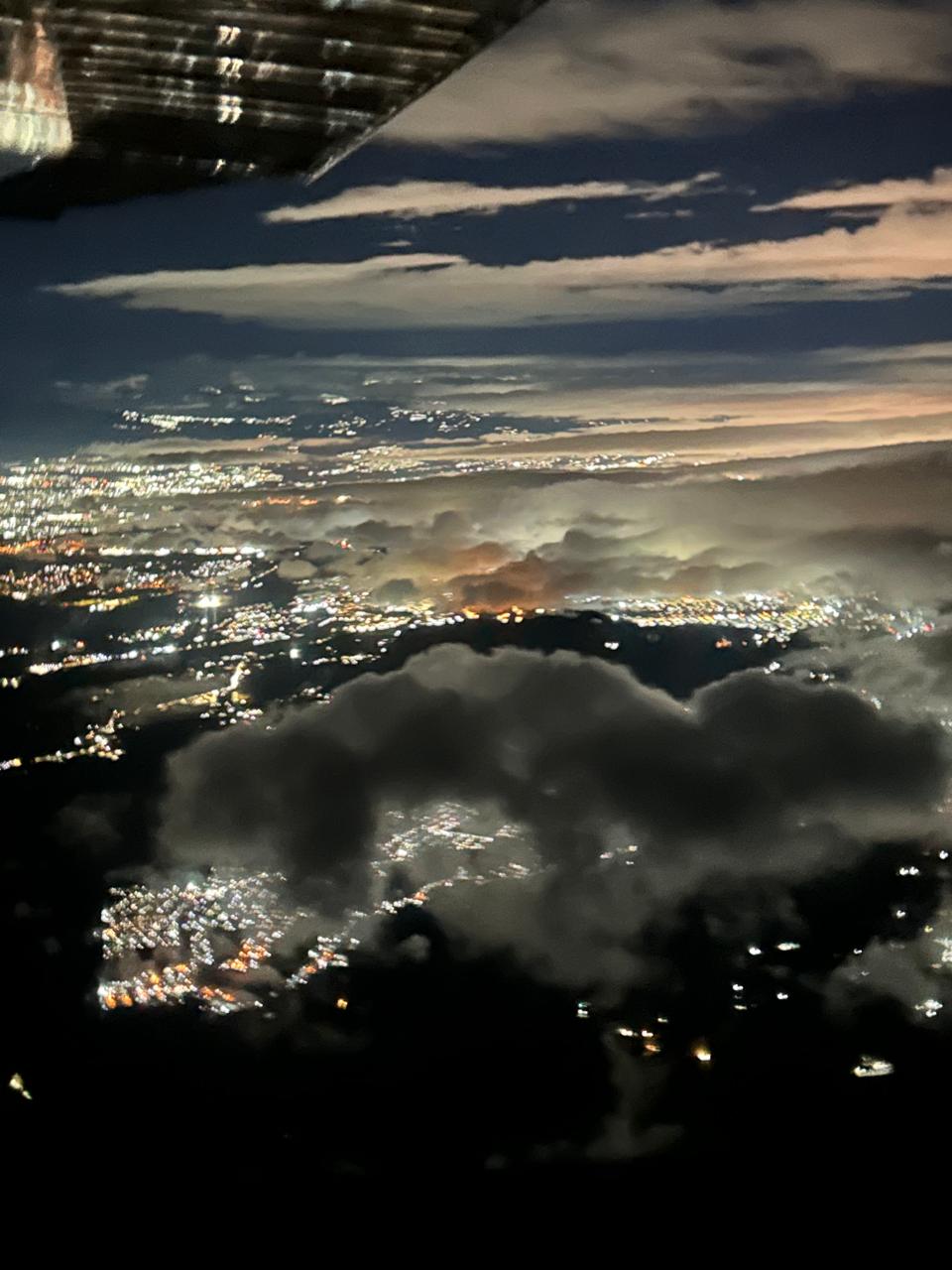 Night aerial through clouds with city lights and twilight sky